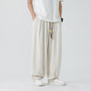 A person wearing beige men's straight leg pants with a drawstring waist