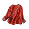 Purple linen wrap top with floral embroidery on a beige background