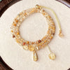 Close up of a multi strand yellow rutilated quartz bracelet with gold tone charms