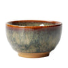 Close up view of a ceramic Jian Zhan tea cup held in hand showing the glaze texture