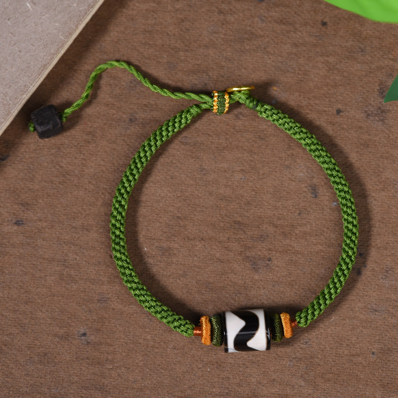 Green braided cord bracelet with a black and white tiger tooth Dzi bead and gold-tone accents