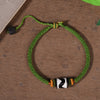 Green braided cord bracelet with a black and white tiger tooth Dzi bead and gold-tone accents