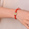 Close-up of a red woven bracelet with a gold hexagonal Bagua charm on a wrist