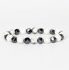A stretch bracelet with alternating white marble and black faceted beads on a white background