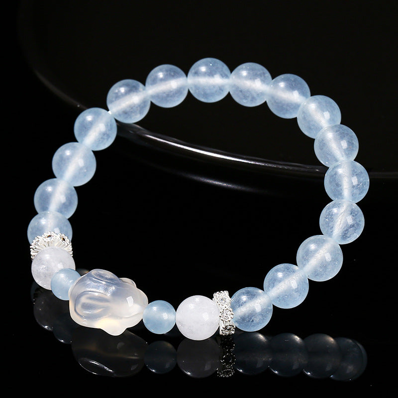 Blue chalcedony beaded bracelet with a white agate rabbit charm on a black background