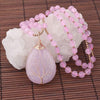 Pink beaded necklace with a purple crystal Tree of Life pendant on a bamboo mat