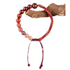 Woven red cord bracelet with gradient crystal beads worn on a wrist