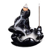 Black ceramic backflow incense burner with white smoke flowing down like a waterfall
