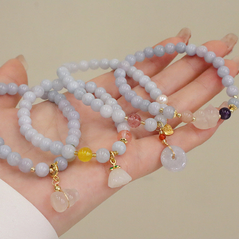 Pale blue beaded bracelets with gold-tone charms on a wrist