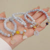 Pale blue beaded bracelets with gold-tone charms on a wrist