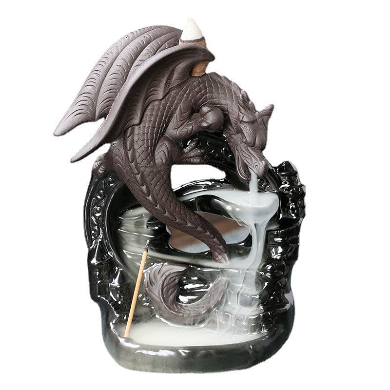 Close up of a black ceramic dragon incense burner with white smoke flowing down like water