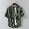 Black men's plain shirt with three quarter sleeves and a chest pocket hanging on a wooden hanger