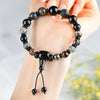 Hand holding a dark mixed crystal beaded bracelet with a knot closure