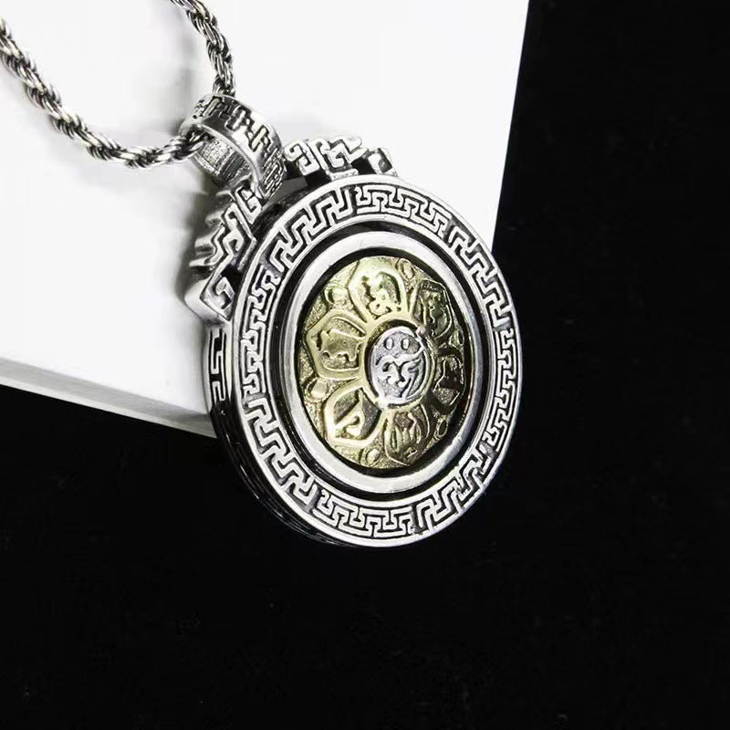 Close up of a silver tone copper pendant with a gold tone center that rotates