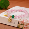 Close-up of pink crystal bracelet with white rabbit charm and gold pendant on a book