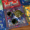 Square embroidered tea mat with blue background and white crane motif under a teapot