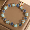 Blue beaded bracelet with gold spacers and a colorful rocking horse charm on a wooden surface