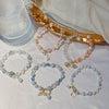Group of pastel beaded bracelets with crystal accents and gold charms on a white cloth