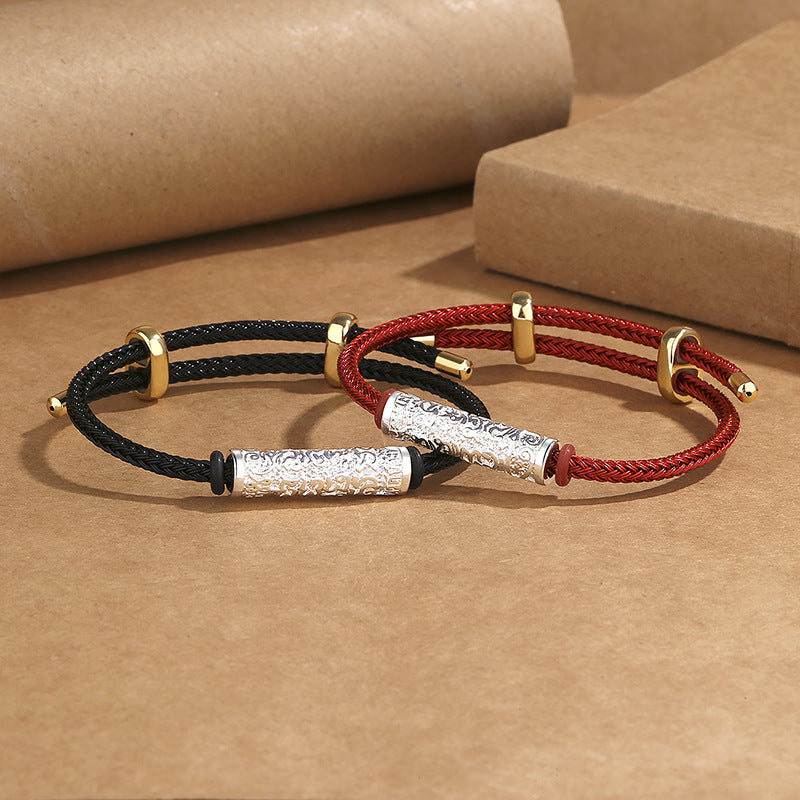 Two braided cord bracelets with textured metal cylinders resting on brown paper