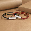 Two braided cord bracelets with textured metal cylinders resting on brown paper
