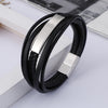 Close-up of a black braided leather bracelet with a silver metal bar on a white surface