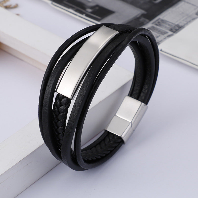 Close-up of a black braided leather bracelet with a silver metal bar on a white surface
