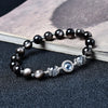 Black obsidian beaded bracelet with a blue stone centerpiece resting on an open book