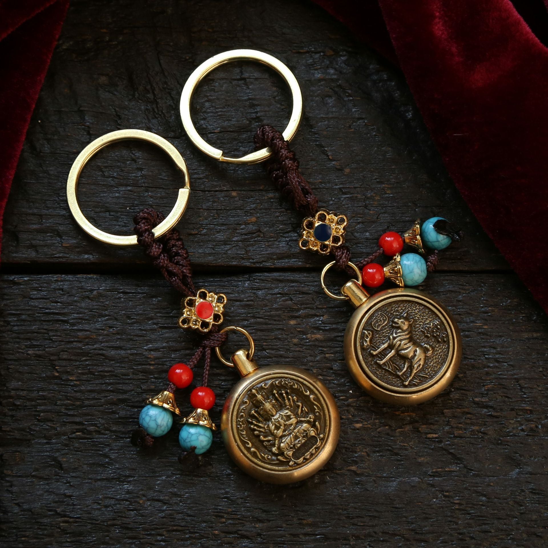 Two brass keychains with spinning zodiac pendants on a dark wood surface
