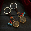 Two brass keychains with spinning zodiac pendants on a dark wood surface