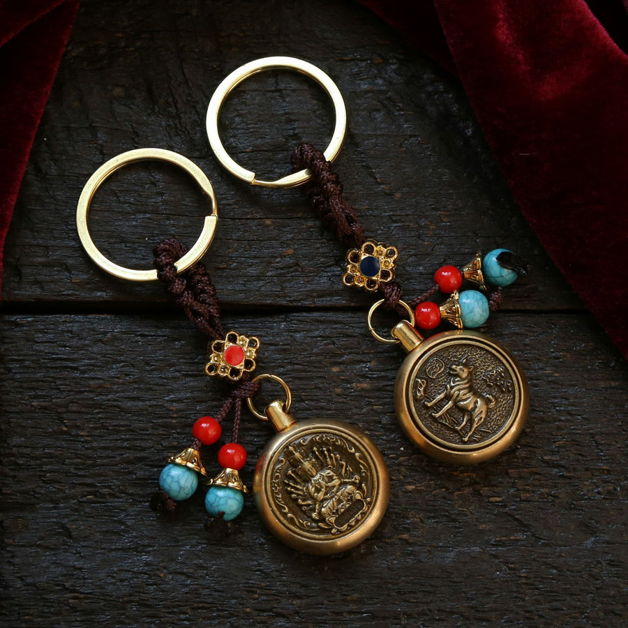 Two brass keychains with spinning zodiac pendants on a dark wood surface