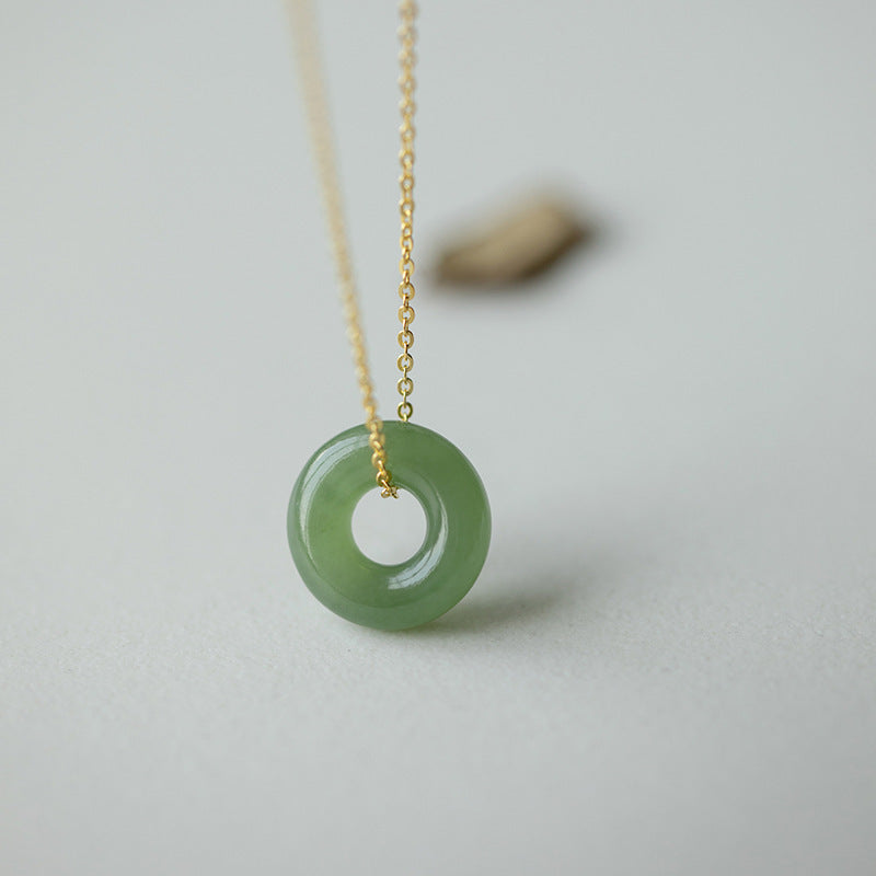Green round Hetian jade peace buckle pendant on a thin gold chain
