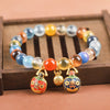 Multi-colored candy agate bead bracelet with gold-tone charms on a wooden tray