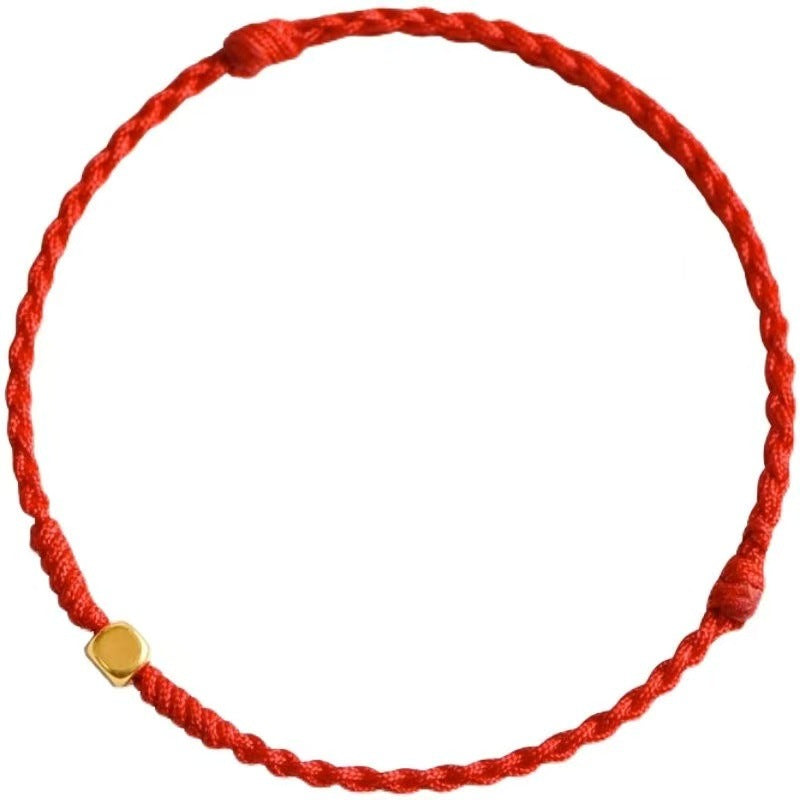 Close-up of a red braided cord bracelet with a small gold square bead