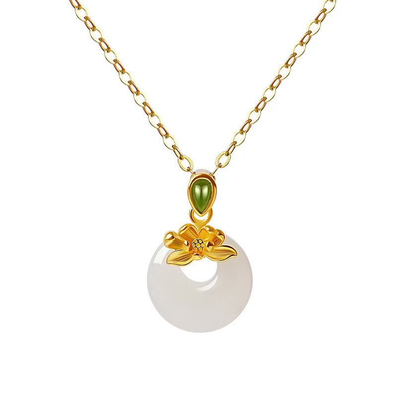Close-up of a gold-tone necklace with a white round pendant and a small gold flower on top