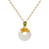 Close-up of a gold-tone necklace with a white round pendant and a small gold flower on top