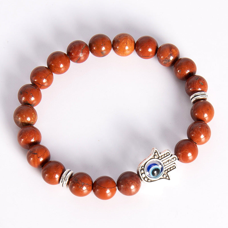 Silver tone Hamsa hand charm with blue evil eye on a beaded stone bracelet