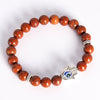 Silver tone Hamsa hand charm with blue evil eye on a beaded stone bracelet