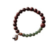 Close up of a rosewood and jade beaded bracelet with a silver lotus charm on a wooden surface