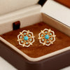 Pair of gold-tone flower stud earrings with blue stones in a jewelry box