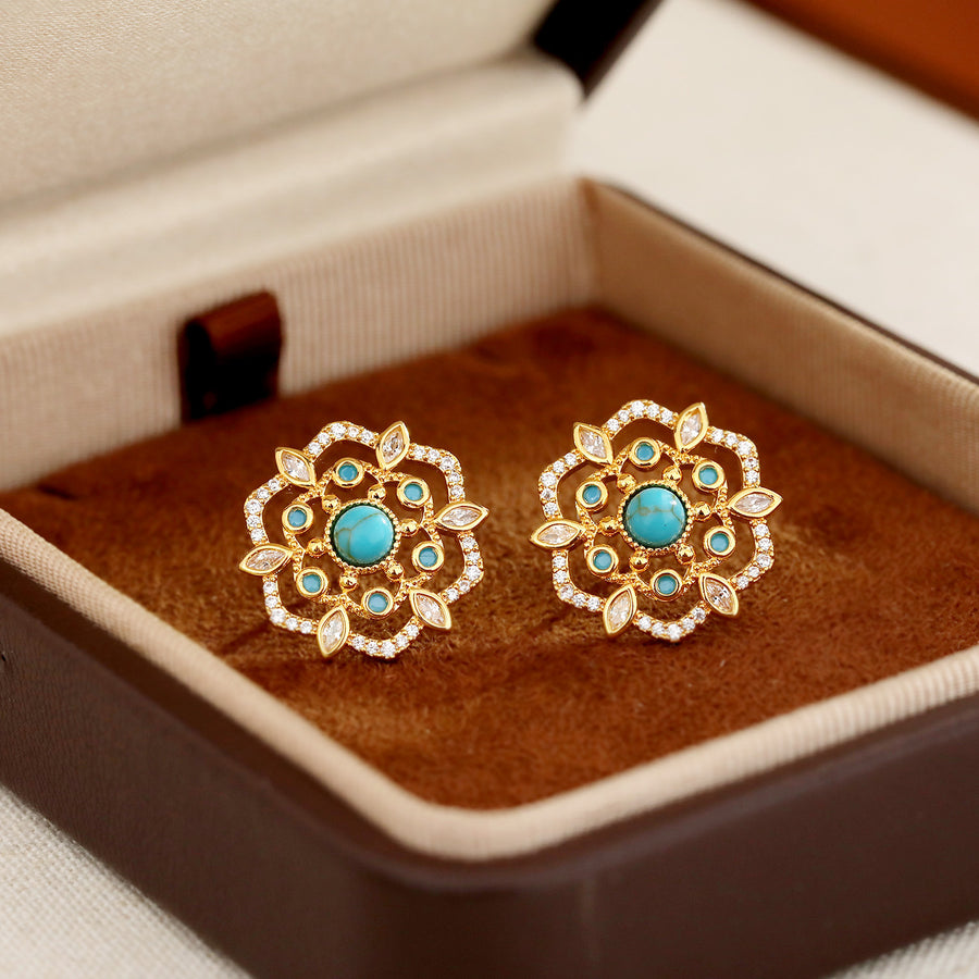Pair of gold-tone flower stud earrings with blue stones in a jewelry box