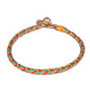 Close up view of a multicolored braided cord bracelet with a silver bead clasp on a red background