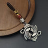 Close up of a vintage copper keychain with a double koi fish charm on a wooden surface.