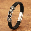 Close-up of a black braided leather bracelet with a silver infinity knot clasp on a wooden surface.