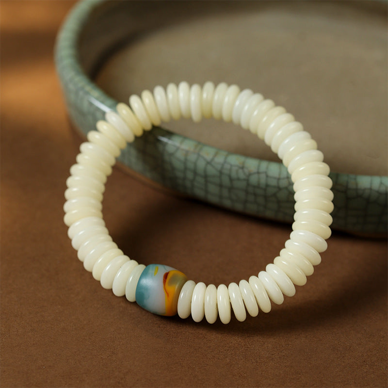 Close up of white flat bodhi seed beads with one colorful accent bead