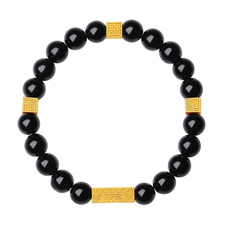 Close up of black obsidian bead bracelet with gold square charms on a wrist