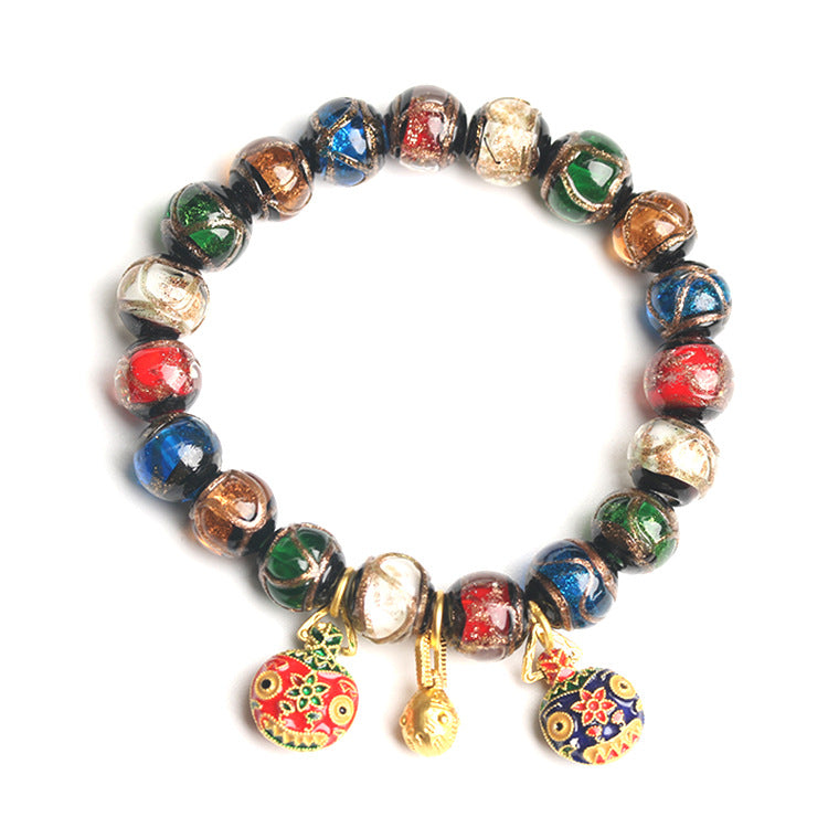 Colorful Liuli glass bead bracelet with gold-tone animal charms on a grey background