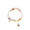 Close-up of a colorful rutilated quartz beaded bracelet with a gold-tone wire band and zircon charm.