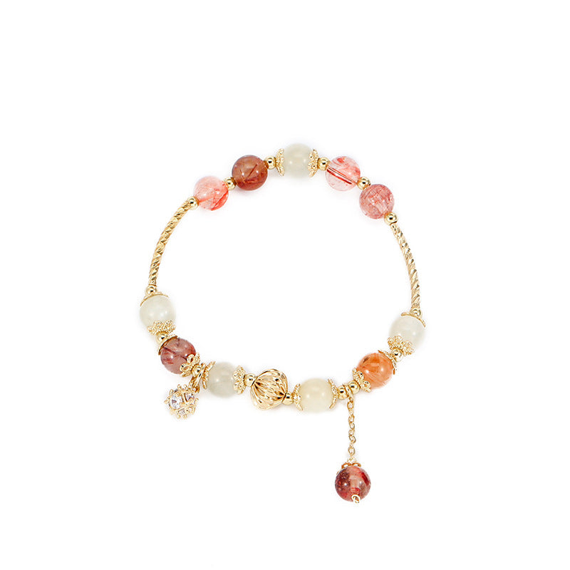 Close-up of a colorful rutilated quartz beaded bracelet with a gold-tone wire band and zircon charm.