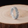 Close up of a silver ring with cloud patterns on a wooden surface