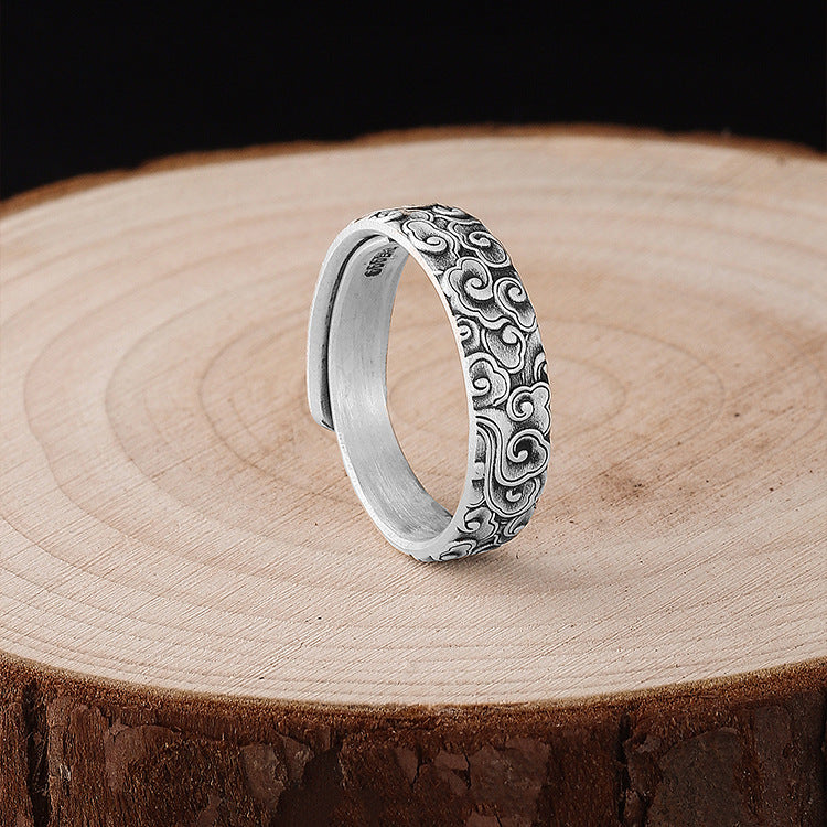 Close up of a silver ring with cloud patterns on a wooden surface